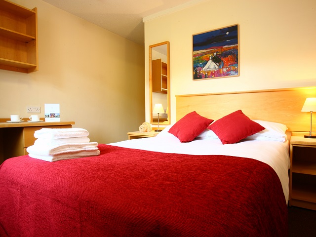 double bed with red bedding and white towels